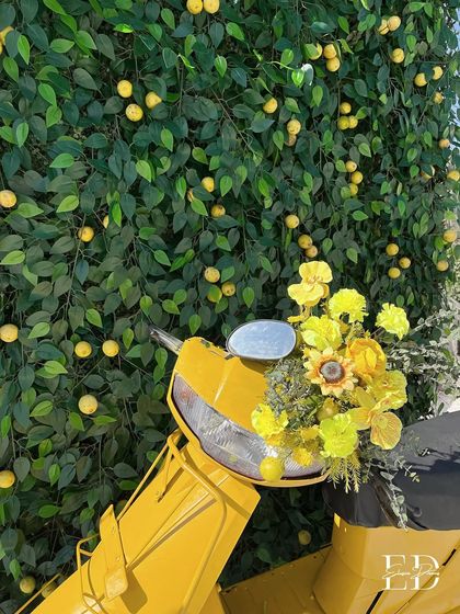 A classic yellow scooter, its basket overflowing with yellow flowers, parked in front of a lush wall of lemon trees. This iconic prop perfectly embodies the spirit of an Italian summer.