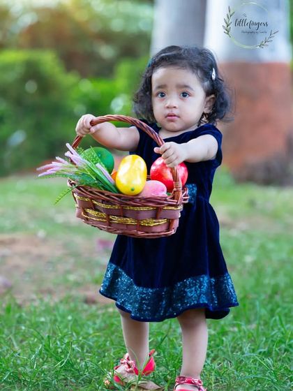 A little girl with a basket of fruit, looking like a treasure herself. The rich colors of her dress and the natural surroundings make for a beautiful and vibrant child portrait.