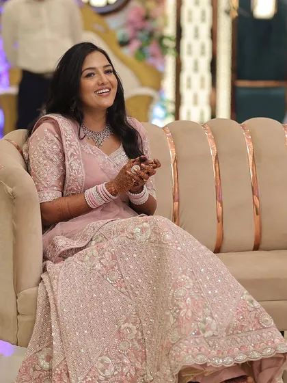 A full view of the pastel pink engagement lehenga and the complementary makeup. The look is cohesive, with a focus on glowing skin and a subtle lip that doesn't overpower the intricate outfit.