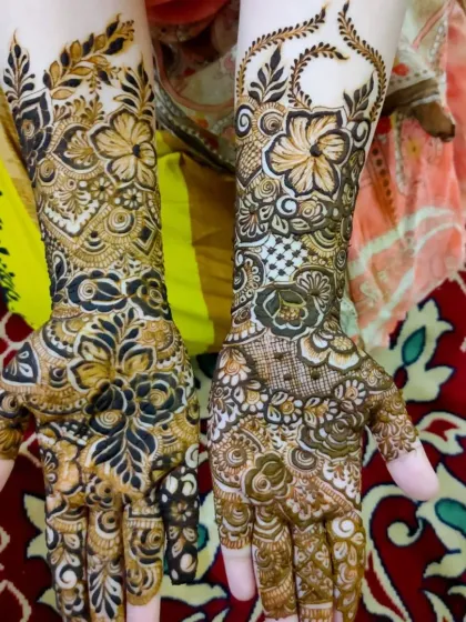 This is a heavy floral bridal design, with bold flower outlines filled with intricate shading and line work. The pattern flows from the palms up to the forearms.