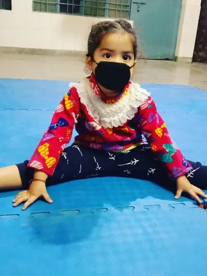 Flexibility is a cornerstone of karate. This young student shows incredible dedication, working on her splits on the dojo mat. We build strong, flexible, and confident kids.
