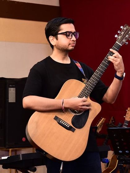 A student confidently performs a piece on his acoustic guitar at our concert. The stage is where all the hard work and practice come to life.