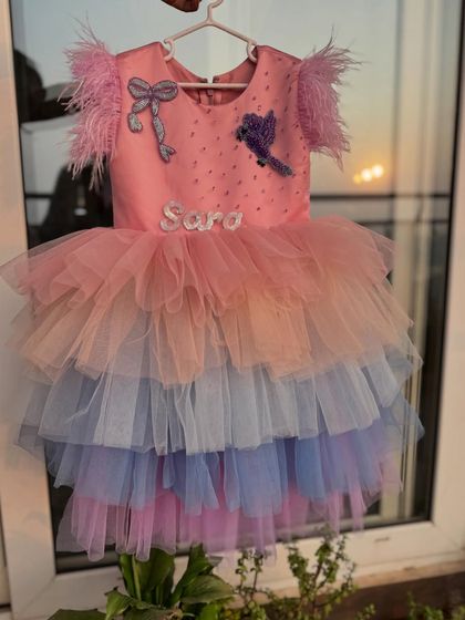 A truly special custom creation. This rainbow-layered tulle dress was personalized with the birthday girl's name, "Sara," and other unique embellishments like a bird and bow.