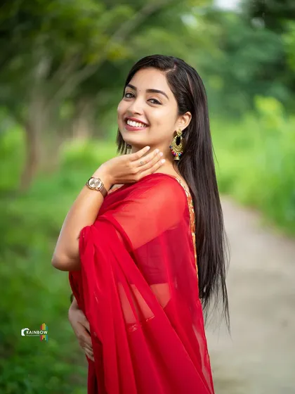 A beautiful shot capturing the model's profile and the flow of her red saree, highlighting her long hair and traditional earrings.