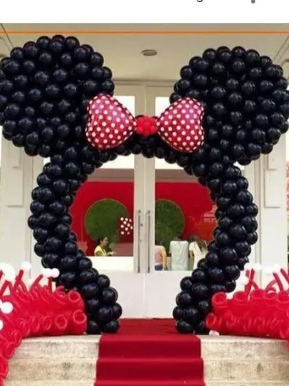 A classic Minnie Mouse themed entrance arch. The iconic Minnie ears and bow are created with black and red balloons, setting the stage for a fun and memorable party.
