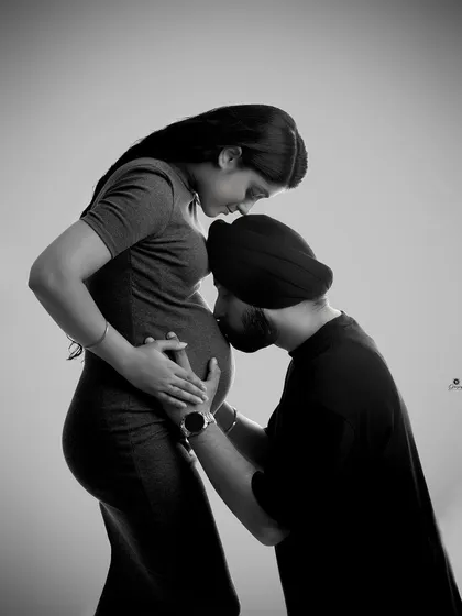 A tender and intimate black and white portrait. The dad-to-be gently kisses the baby bump, creating a powerful and emotional image of love and connection.