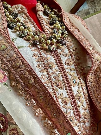 A close-up of the neckline, showing the detailed Doriwork and how it complements the floral embroidery.