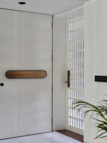 The main door is a statement piece, with a custom-designed long handle with a brass finish that adds a touch of luxury to the minimalist design.