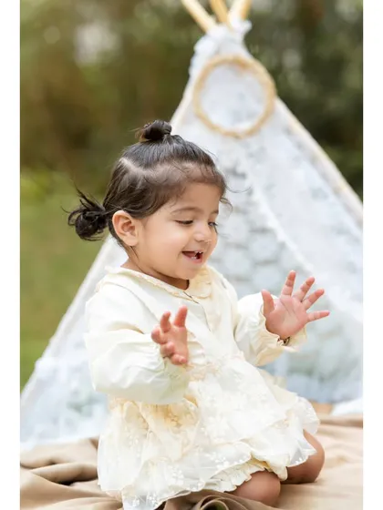 The pure joy of play. Little Aanshi claps her hands with a happy smile during her pre-birthday twin photoshoot, with a lovely teepee creating a soft backdrop.