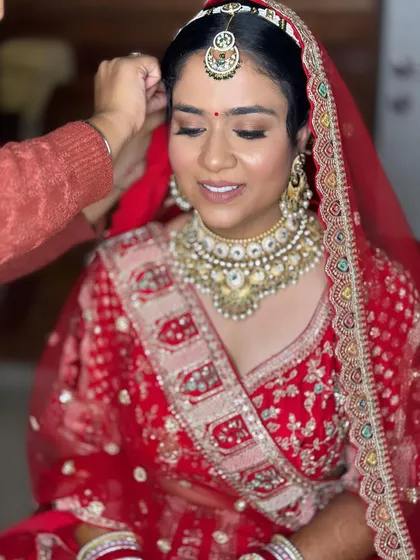 A behind-the-scenes moment of setting the dupatta. The makeup is already flawless and ready for the final touches.