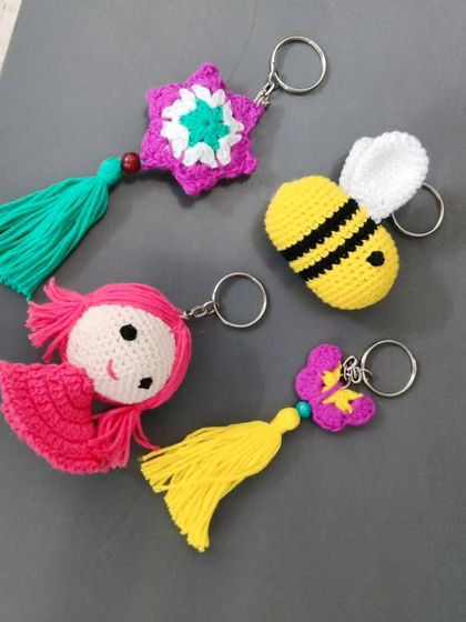 A few of my different keychain designs together. You can see a honey bee, a little doll face, a star, and a flower, all with colourful tassels. Each one is a unique piece of handmade art.
