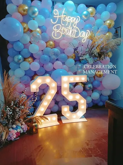 A gorgeous balloon wall in pastel blue, pink, and gold for a 25th birthday. The large marquee numbers and pampas grass accents give this photo backdrop a trendy and celebratory feel.