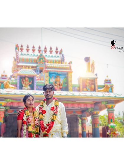A formal portrait of the couple in front of the temple. This wide shot captures both the couple and the impressive temple architecture, documenting the location of their sacred ceremony.