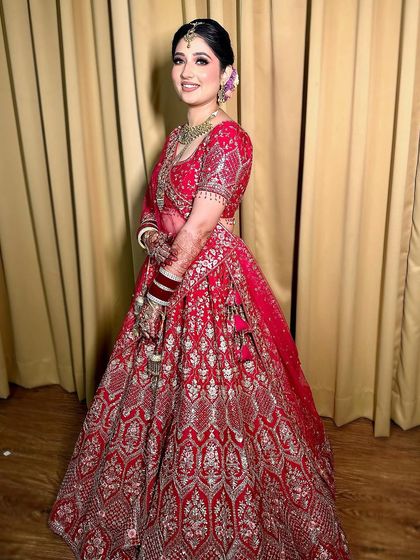 Simply enchanting. This bride glows in her beautiful red and silver lehenga, with a soft glam makeup look that enhances her smile.