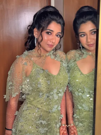 The client looking stunning in her green embellished gown, her hair styled in a chic half-ponytail.