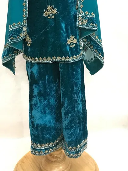 A close-up of the bottom half of the velvet suit, showing the detailed embroidery on the hem of the pants and kurta.