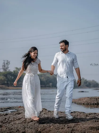 A happy, carefree walk along the riverbank. Holding hands and smiling, this photo captures the easy, natural chemistry of the couple in an outdoor setting.