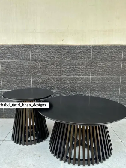A nesting set of a coffee table and side table, both with a black finish and a slatted base.