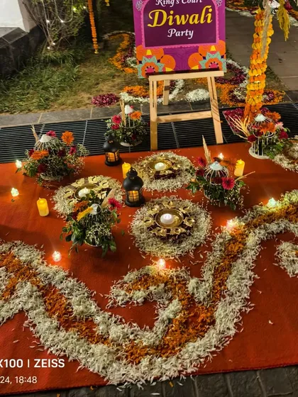 A beautiful entrance arrangement for the Diwali party, with intricate floral rangoli, candles, and lanterns.