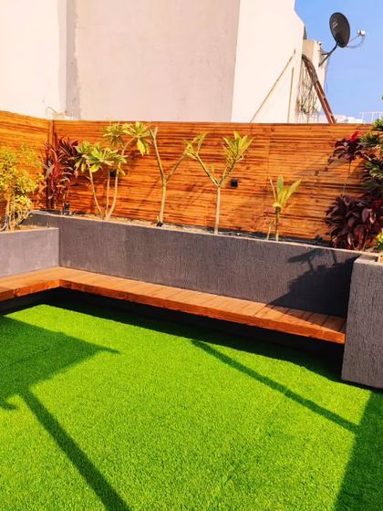 A custom L-shaped bench made from thermopine wood, with an integrated planter. The back wall is also clad in pinewood for a cohesive look.