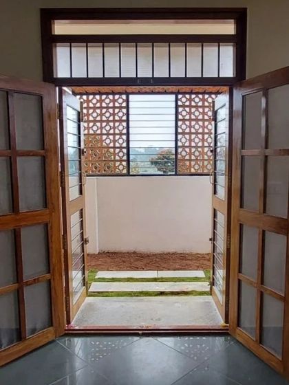 Double doors open to a small patio, with a jaali screen providing a decorative and functional backdrop.