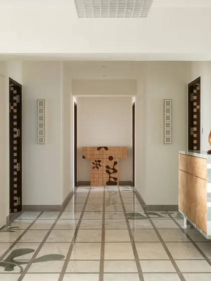 This foyer in our 'Gingham Dreams' project features a marble grid floor that leads to the bedrooms. The space is bookended by a study and a custom veneer console, with geometric motifs on the ceiling mirroring the floor pattern.