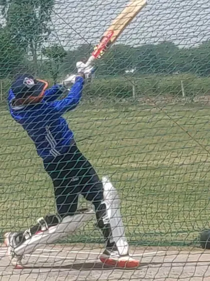 A young player practicing his lofted shots in the nets. Power hitting is a key component of modern cricket, and we train it extensively.