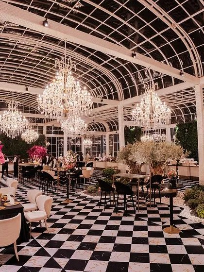Modern luxury defined by light and structure. I designed this pre-wedding event within a magnificent glasshouse, using a bold checkered floor, dozens of crystal chandeliers, and dramatic floral arrangements to create a chic and unforgettable atmosphere.