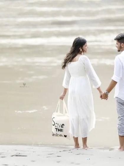 A quiet, reflective moment as the couple looks out at the water, holding their "Save the Date" bag. It’s a beautiful and meaningful shot.
