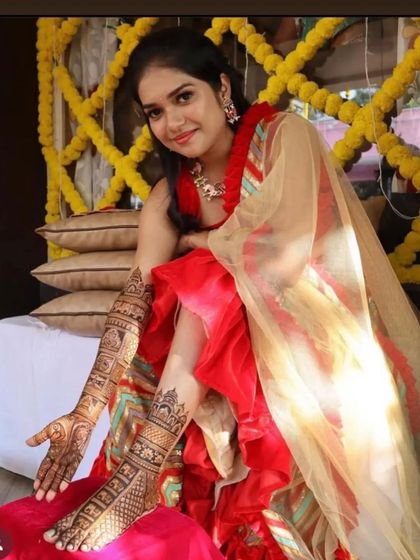 A stunning photo of a bride in her mehendi outfit, showcasing her full hand and leg mehendi.