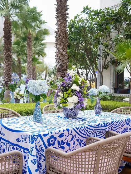 A full view of a dining table setup, showing the wicker chairs that add a touch of relaxed, outdoor elegance to the otherwise regal theme.