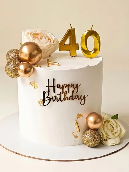 An elegant 40th birthday cake in white and gold. This design features fresh roses, gold chocolate spheres, and delicate gold leaf accents for a touch of luxury.