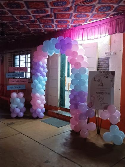 A full view of the entrance setup for a baby shower in a hall. The pastel balloon arch and welcome sign guide guests into the celebration area.
