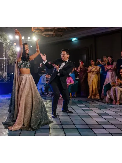 Nick and Shachi do their first dance at the sangeet. Their joyful moves and the cheering crowd create a fun and energetic atmosphere.