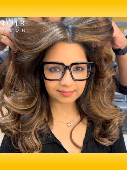 A stunning hair color transformation that proves great hair looks amazing with glasses too. The voluminous curls and caramel highlights frame her face perfectly.