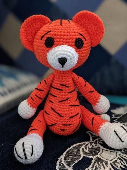 The orange tiger toy sitting on a blue patterned surface.