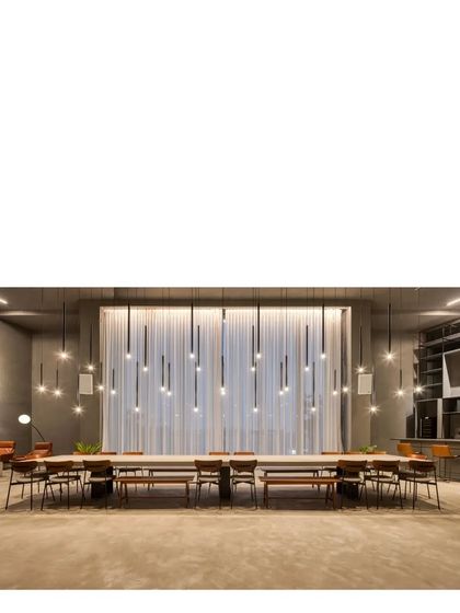 The communal table in our elemental gallery space. The room is designed to be highly adaptable, with seamless gray concrete surfaces and dramatic lighting that can be configured for parties, exhibitions, or gatherings.