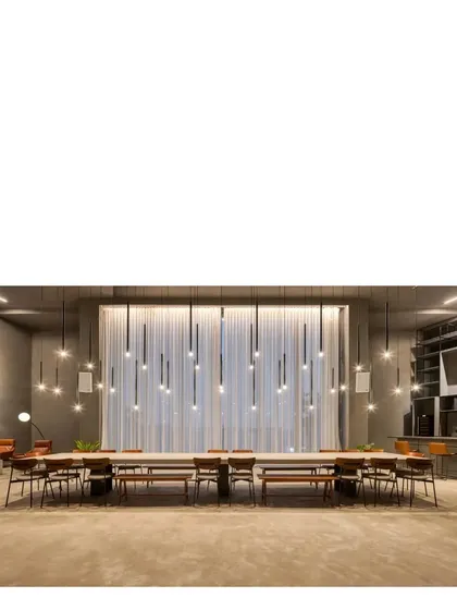The communal table in the gray concrete gallery space, illuminated by a custom installation of pendant lights. This space is designed for get-togethers of every kind, from art exhibits to large dinner parties.