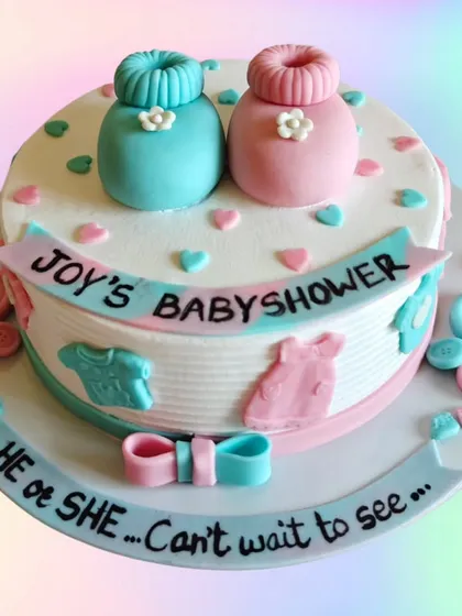 A cute "He or She" baby shower cake with little booties and buttons. The design is simple, sweet, and perfect for celebrating the mom-to-be.