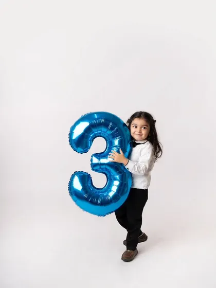 Hugging his giant number three balloon. Props like these give toddlers something to interact with, making the session fun for them.