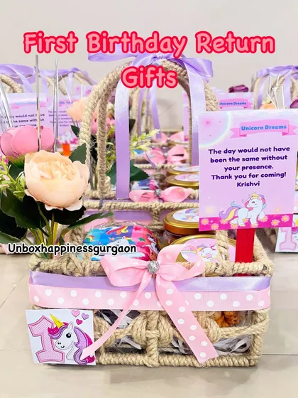 "First Birthday Return Gifts" with a magical unicorn theme. This basket is decorated with a number "1" tag and a pink polka-dot ribbon.