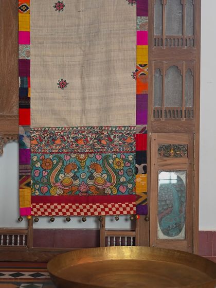 The full runner displayed against a vintage wooden jharokha, showcasing its length and artistry.