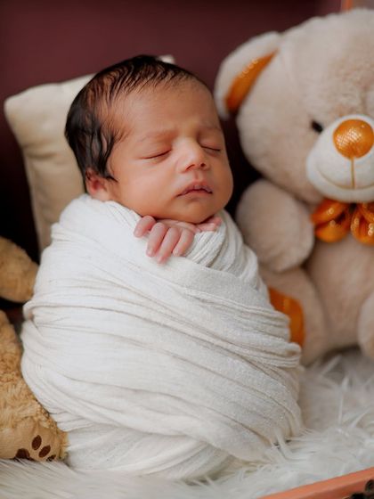 A detailed close-up of a swaddled newborn's face. This angle allows us to appreciate the delicate features, from the soft hair to the tiny hands, all while the baby dreams peacefully.
