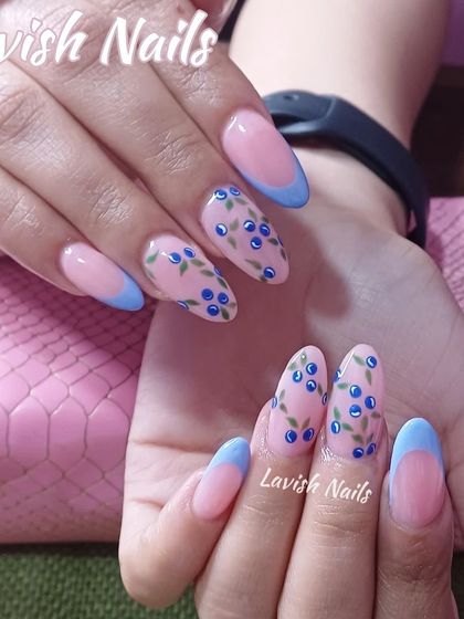 A cute and summery design featuring a light blue French tip and hand-painted blueberry branches on almond nails.