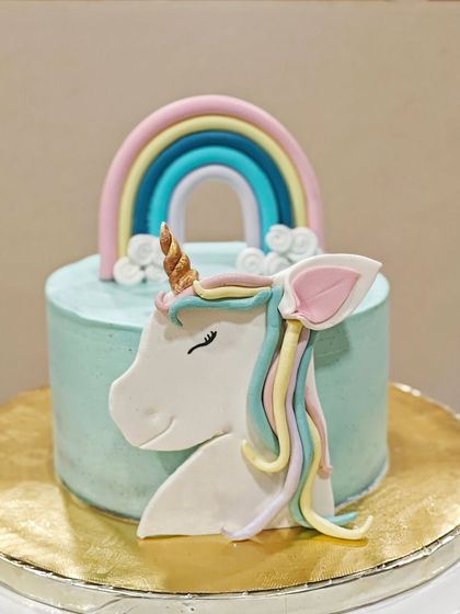A full view of the unicorn theme cake. The simple, smooth buttercream finish makes the colorful fondant details really stand out.