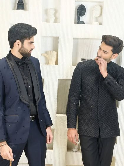 A candid moment between two men dressed in my formal designs. The image captures the social elegance and confidence that my bespoke clothing inspires.