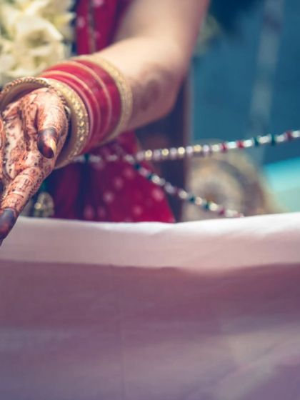 A detail shot of a bride's hands during a wedding ritual. The focus on the henna and the traditional elements tells a story of cultural significance.