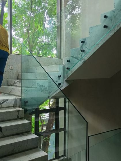 A side-mounted glass railing on a marble staircase. This installation method creates a clean, floating effect, enhancing the modern aesthetic of the interior.