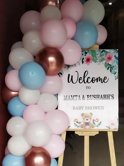 A personalized welcome sign for a baby shower, decorated with a simple arrangement of pastel balloons.