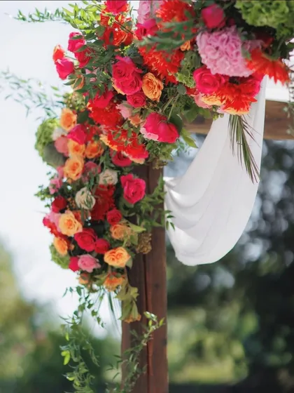 Another close-up of the vibrant floral decor on the wooden mandap, highlighting the texture and color combination of the flowers against the soft white draping. This shows our attention to detail in floral design.